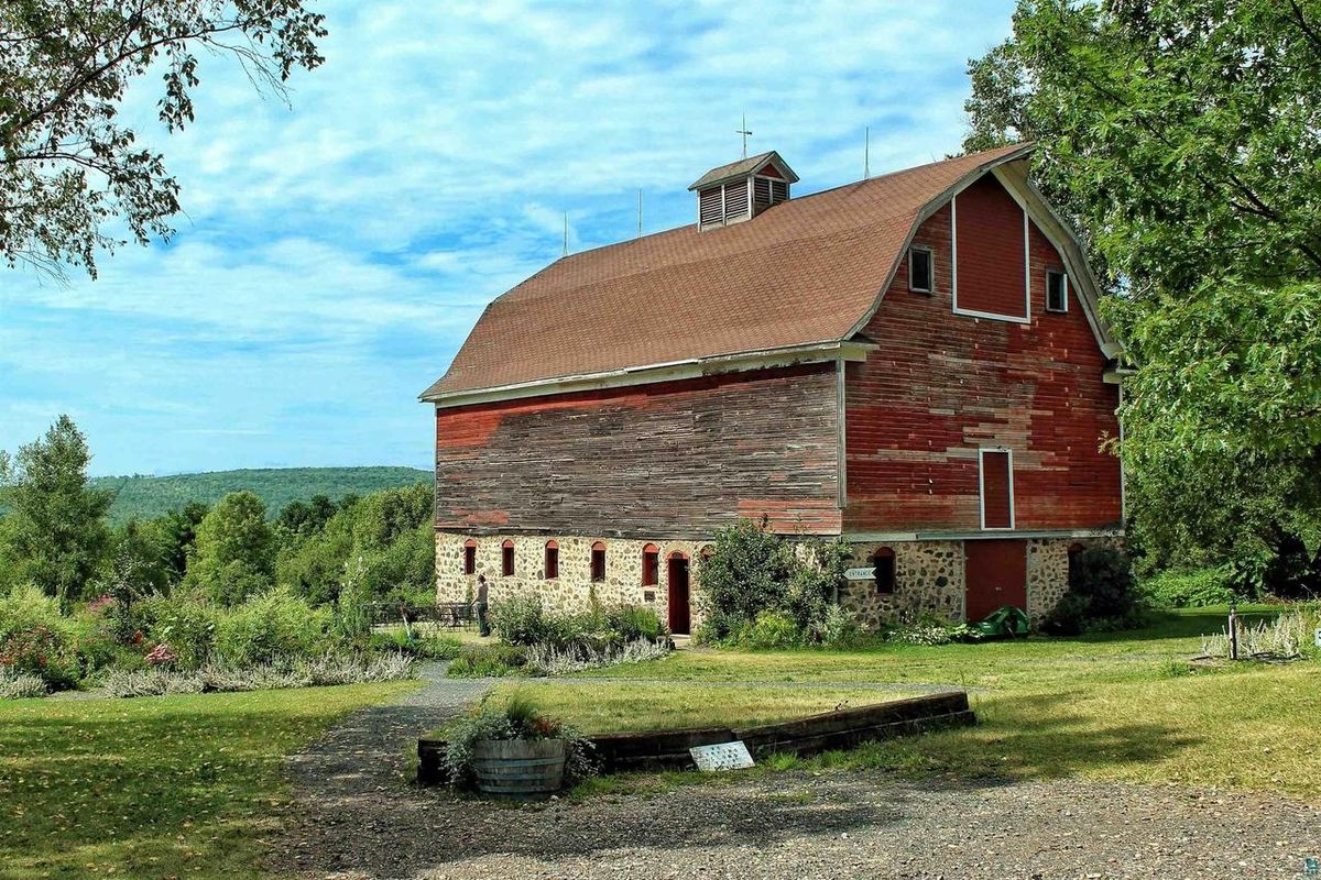 The red barn with its stone foundation and cupola under a blue sky.