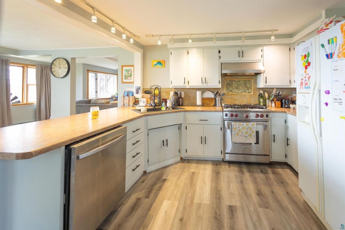 Kitchen with white cabinets, a wood counter, and a stainless range.