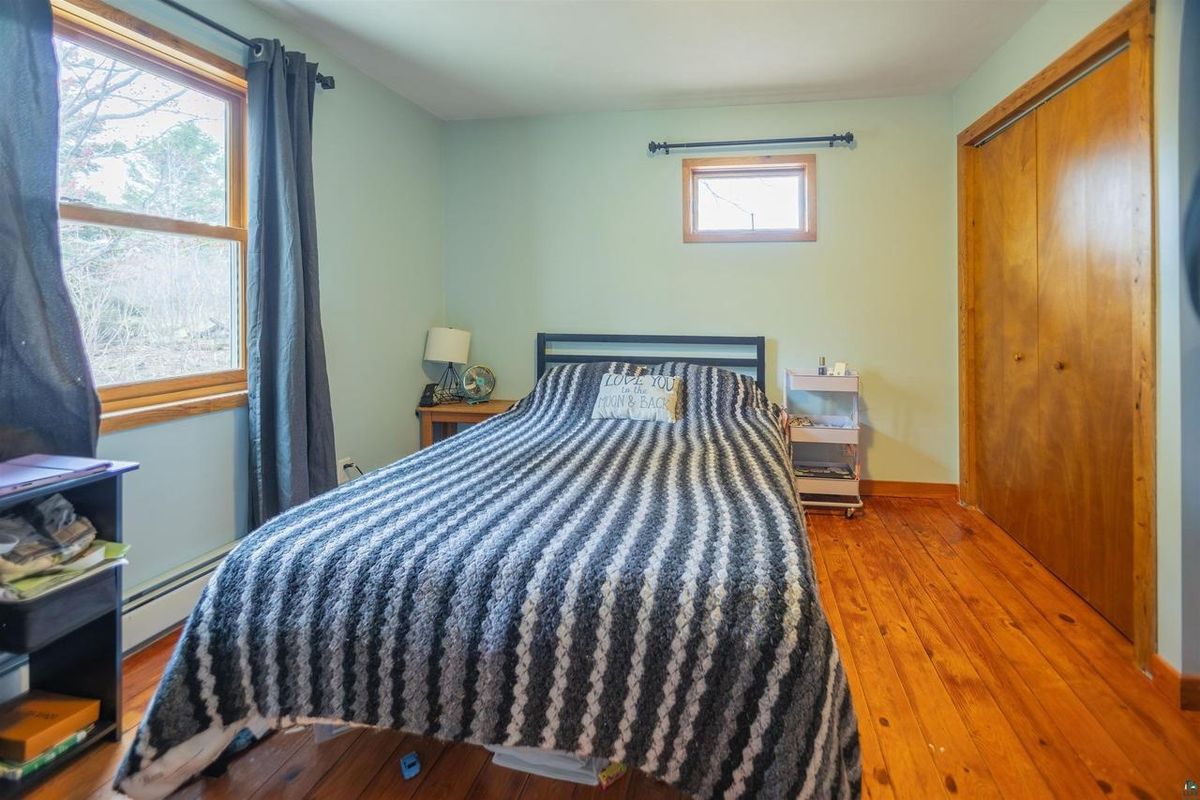 Bedroom with wood floors and windows on two sides.