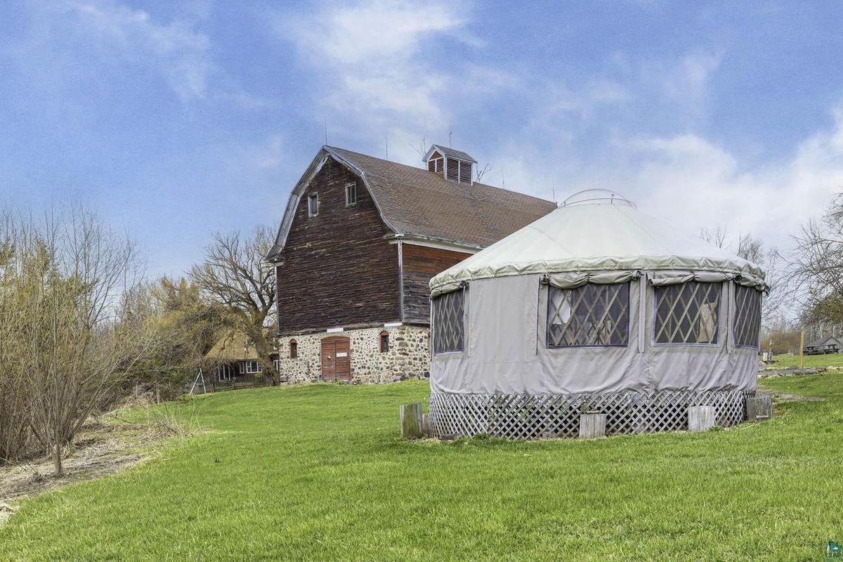 The barn and the yurt on the lawn, with trees behind.