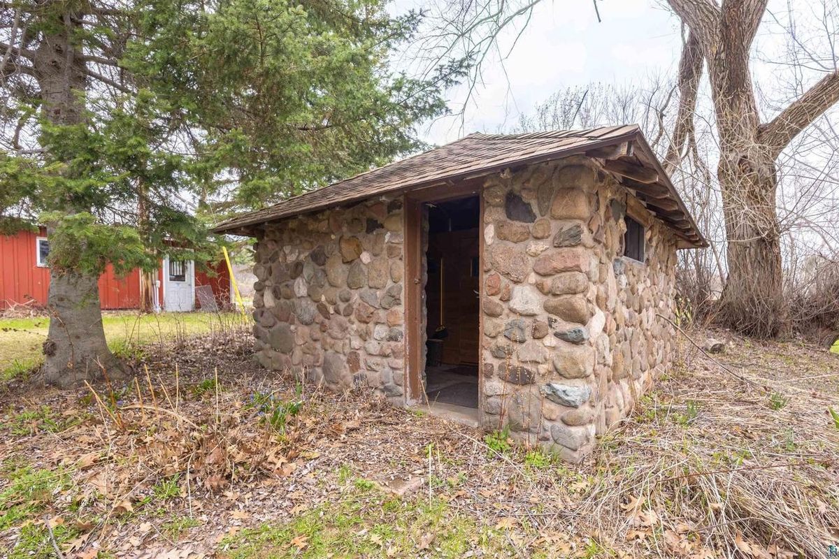 The old fieldstone milkhouse, now a sauna, under a large tree.